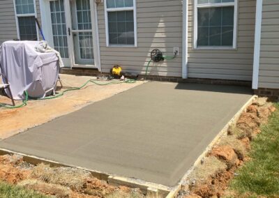 A newly poured concrete patio in front of a house, adding a functional and stylish outdoor space.