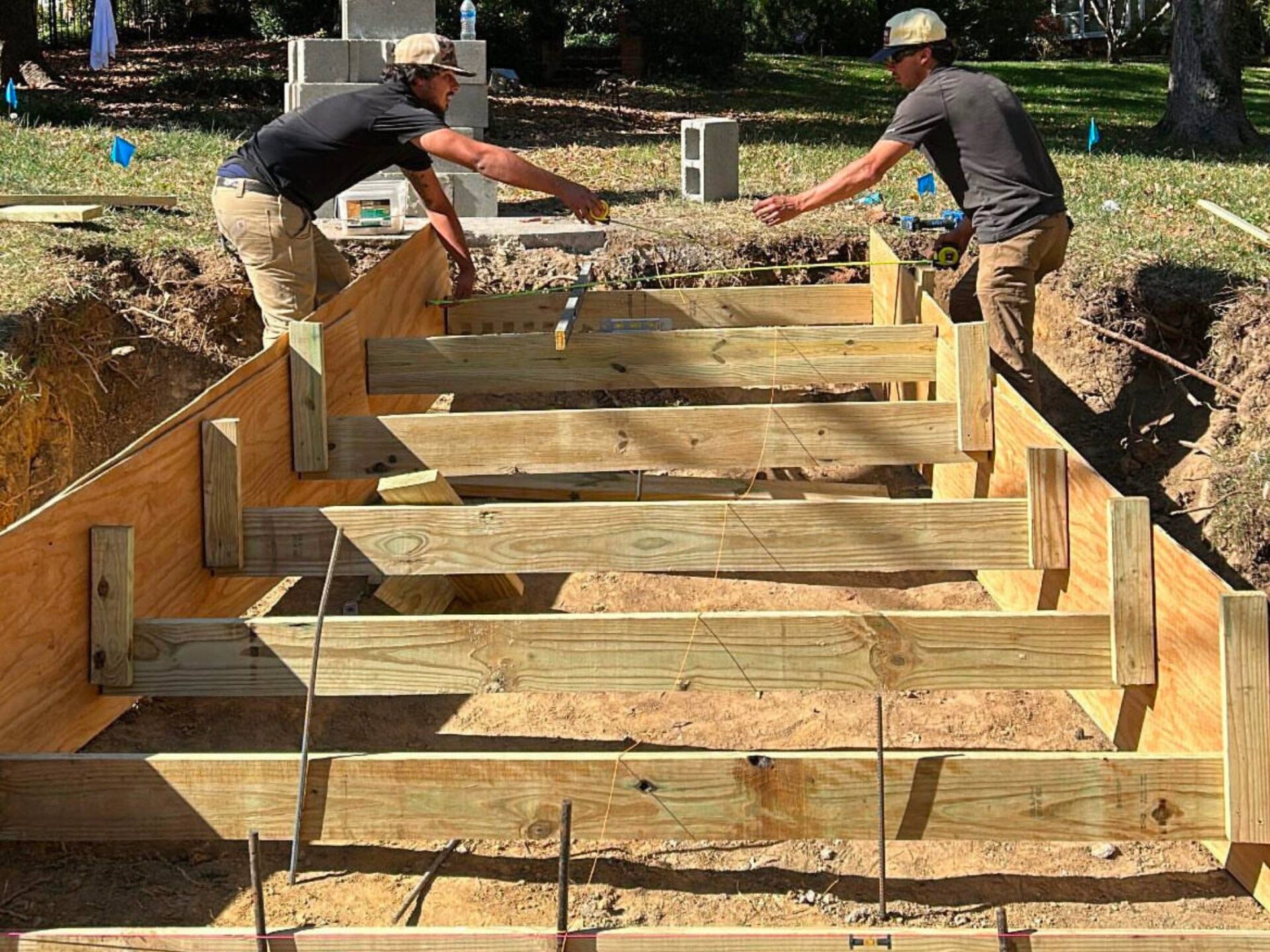 Two men constructing a wooden structure in a yard, showcasing their craftsmanship and teamwork.