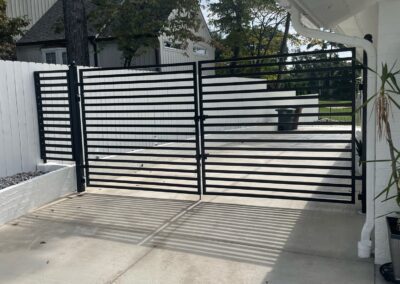 A black and white gate at the entrance of a driveway.
