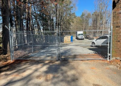 An open gate reveals a parking lot with a parked truck in the driveway.