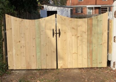 Two wooden gates in a yard with leaves on the ground.