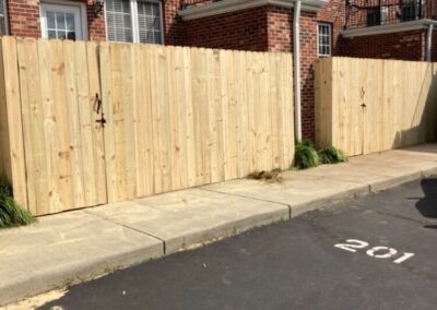 A wooden fence stands in front of a brick building, creating a rustic and charming scene.