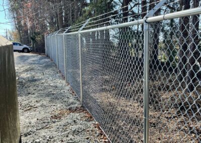 A chain link fence separates a parking lot, providing security and boundary.