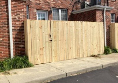 A wooden fence stands in front of a brick building, creating a rustic and charming scene.