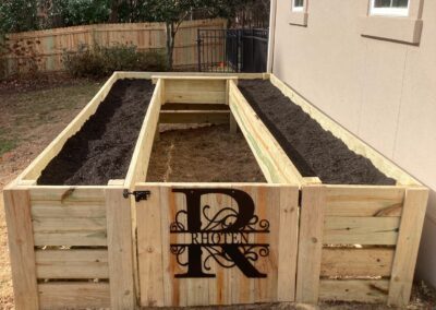 A raised garden box with the initials "R" on it, providing a personalized touch to the green space.
