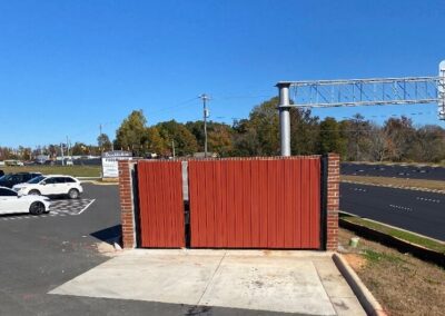 A red gate stands before a parking lot, offering entry and exit to vehicles.